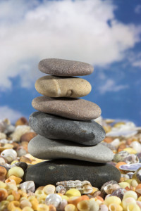 Zen stones on yellow and orange sea shells against a cloudy sky with copy space above